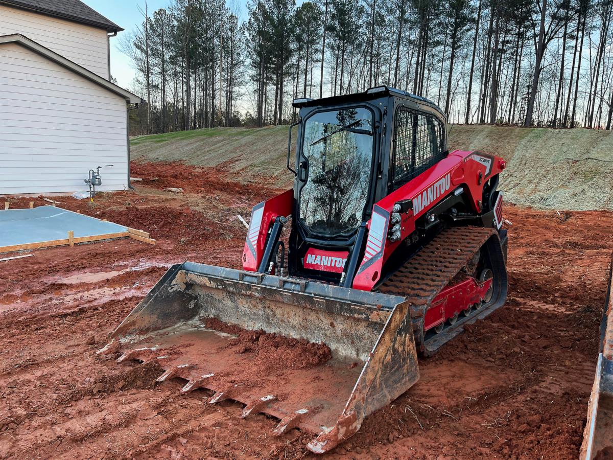 Manitou compact track loader with a bucket working the dirt