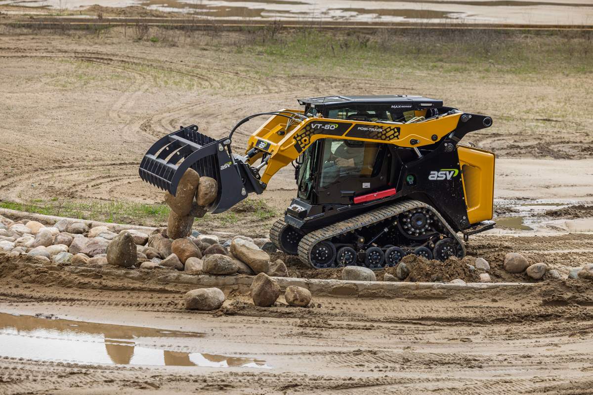 ASV compact track loader with a grapple attachment lifting rocks